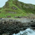 people standing on rock formation near body of water during daytime