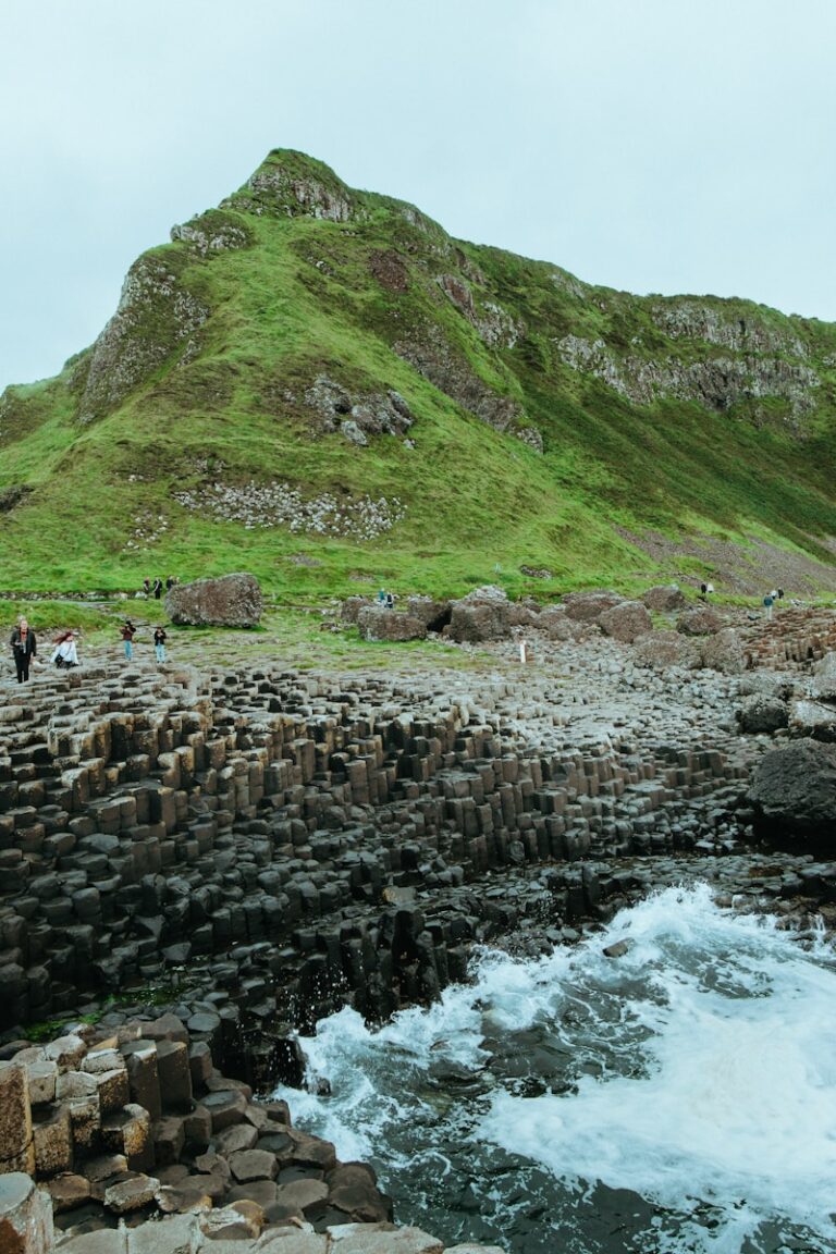 people standing on rock formation near body of water during daytime