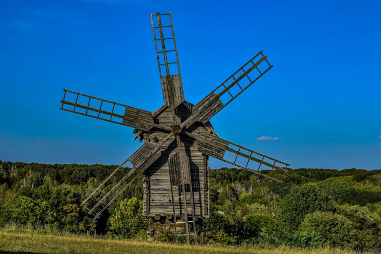 an old wooden windmill in a grassy field