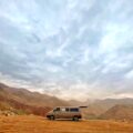 a van is parked in a field with mountains in the background