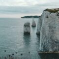 gray rock formation on sea under white clouds during daytime