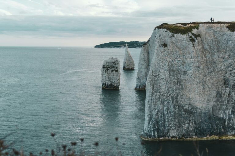 gray rock formation on sea under white clouds during daytime