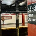 a person standing on a train platform next to a sign