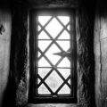 A black and white photo of a window in a stone wall