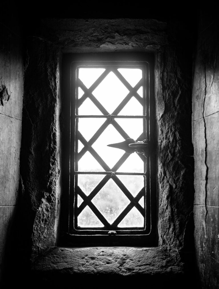 A black and white photo of a window in a stone wall