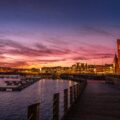 body of water near city buildings during sunset