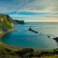 green and brown mountain beside blue sea under blue sky during daytime