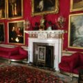 a living room with red walls and paintings on the wall