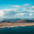 brown mountain near body of water under blue sky during daytime