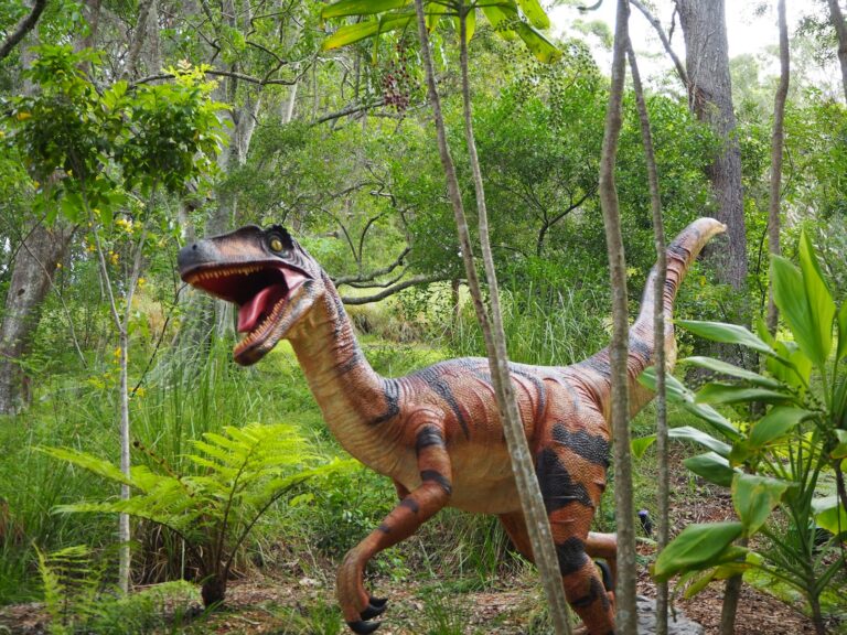 brown and black dinosaur statue on forest during daytime