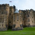 a castle with a flag on top with Alnwick Castle in the background