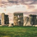 gray rock formation on green grass field under gray cloudy sky