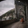 a woman in an orange dress is walking through an archway
