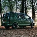 a green van is parked in the woods