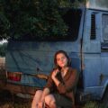 a woman sitting on the ground next to a van