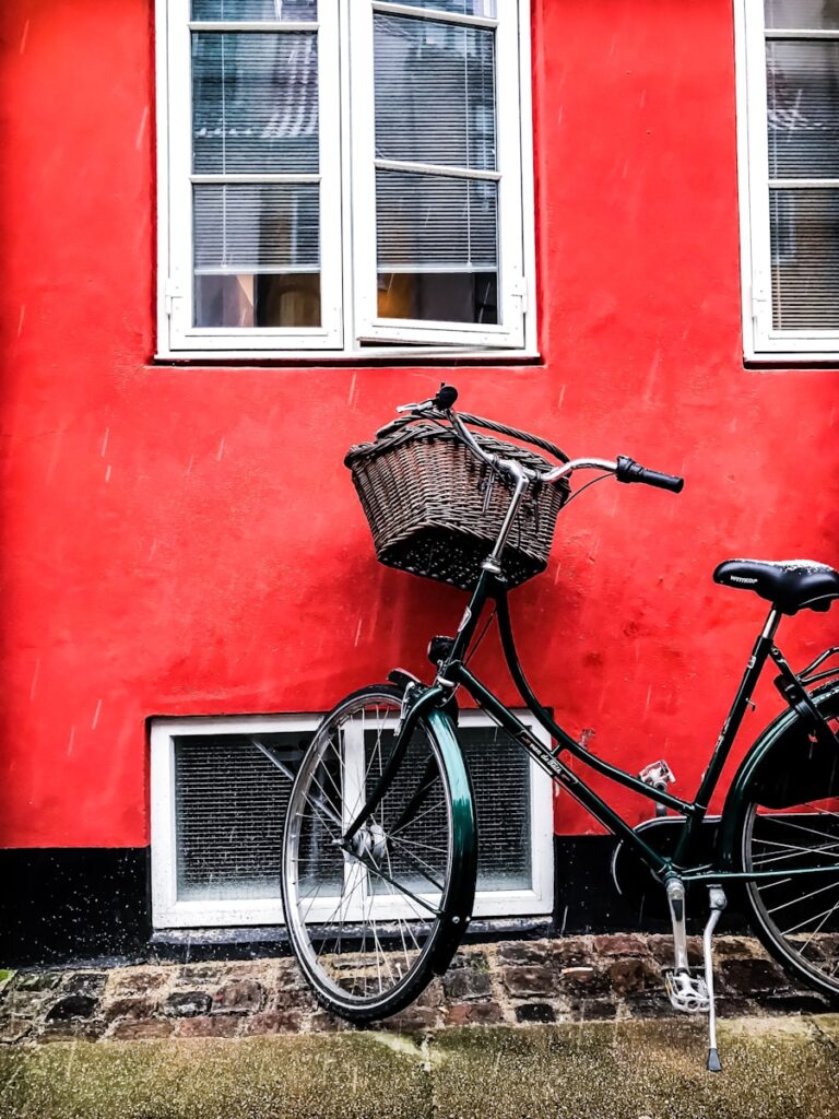 black cruiser bicycle beside red wall