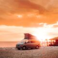 a van parked on the beach at sunset